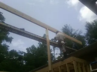 Carpenter setting a ridge beam over a new addition frame — Ice Dam Removal by Roofing Brothers in Comstock Park
