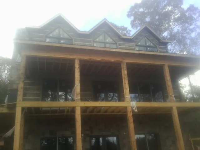 Dormers and porch framing on a large log home under construction — Roof Coating work by our crew in Comstock Park