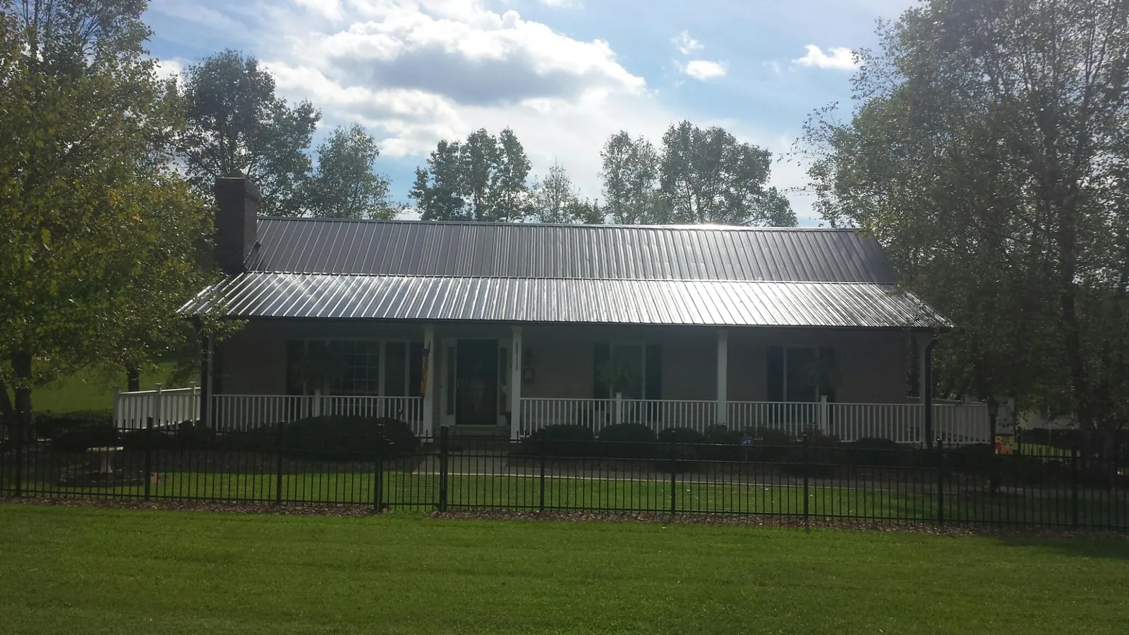 Gray metal roof on a brick ranch with a full width front porch — Gutter Guard Installation work by our crew in Comstock Park