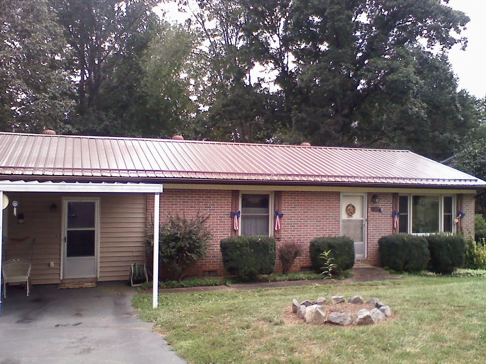 Bronze metal roof and carport on a brick ranch home — Roof Repair work by our crew in Comstock Park