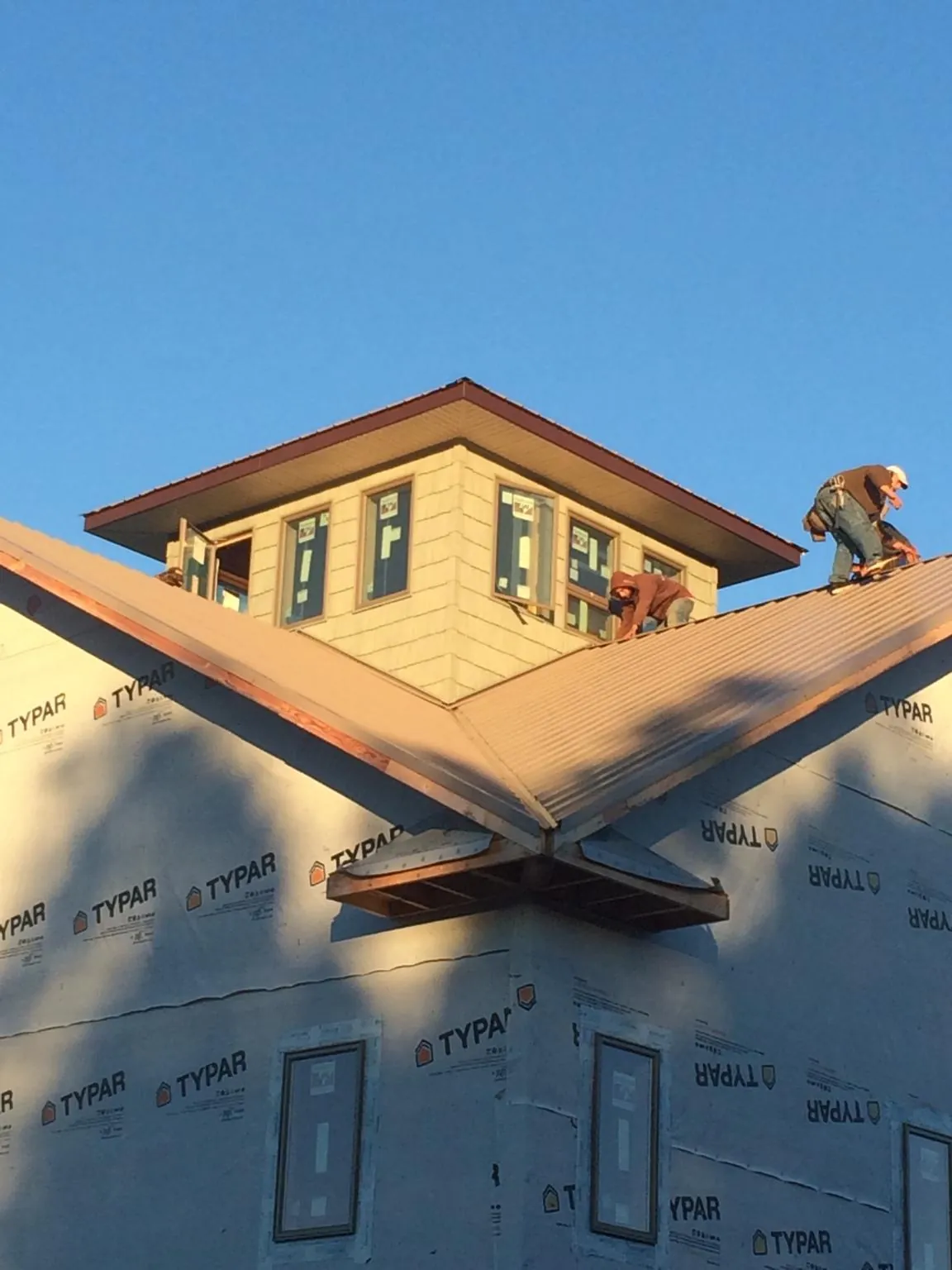 Roofers working around a rooftop cupola on a new metal roof at sunset — Roof Waterproofing in Comstock Park by Roofing Brothers